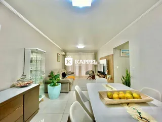 Sala de estar com sofá e mesa de jantar em um ambiente claro.