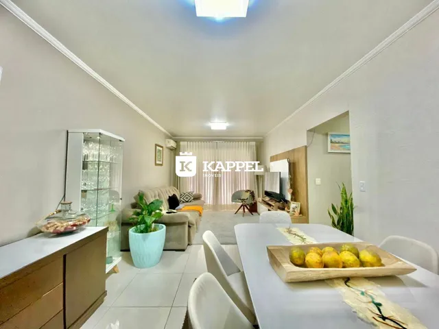 Sala de estar com sofá e mesa de jantar em um ambiente claro.