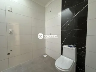 Foto de um banheiro com revestimento de azulejos brancos e um vaso sanitário branco.