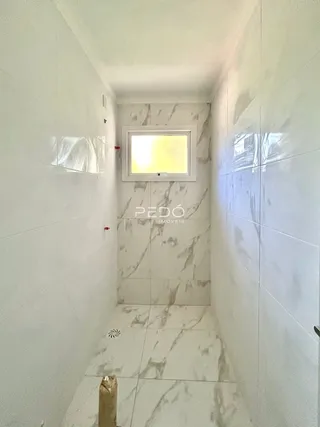Corredor interno com paredes brancas e piso claro.