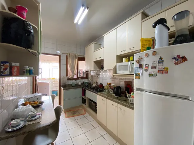 Imagem de uma cozinha iluminada com armários brancos e piso de cerâmica.