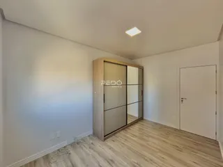 Ambiente interno com piso de madeira clara e paredes brancas.
