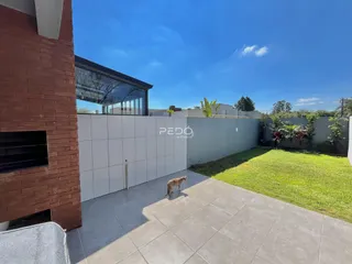 Fachada de uma residência com muro branco e jardim gramado.