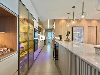 Cozinha moderna com ilha de mármore e armários em madeira clara.