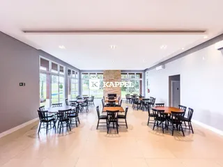 Sala de jantar ampla com mesas e cadeiras em um ambiente claro com vista para o exterior.