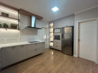 Vista da cozinha moderna com armários brancos e piso de madeira clara.