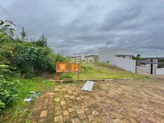 Vista externa de uma propriedade com jardim e área pavimentada.