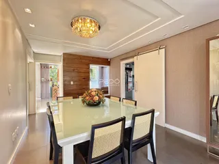 Ambiente de jantar com mesa de vidro e cadeiras de madeira na residência.