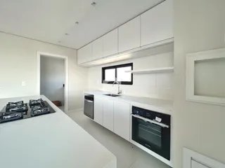 Foto de uma cozinha moderna com armários brancos e bancadas claras.