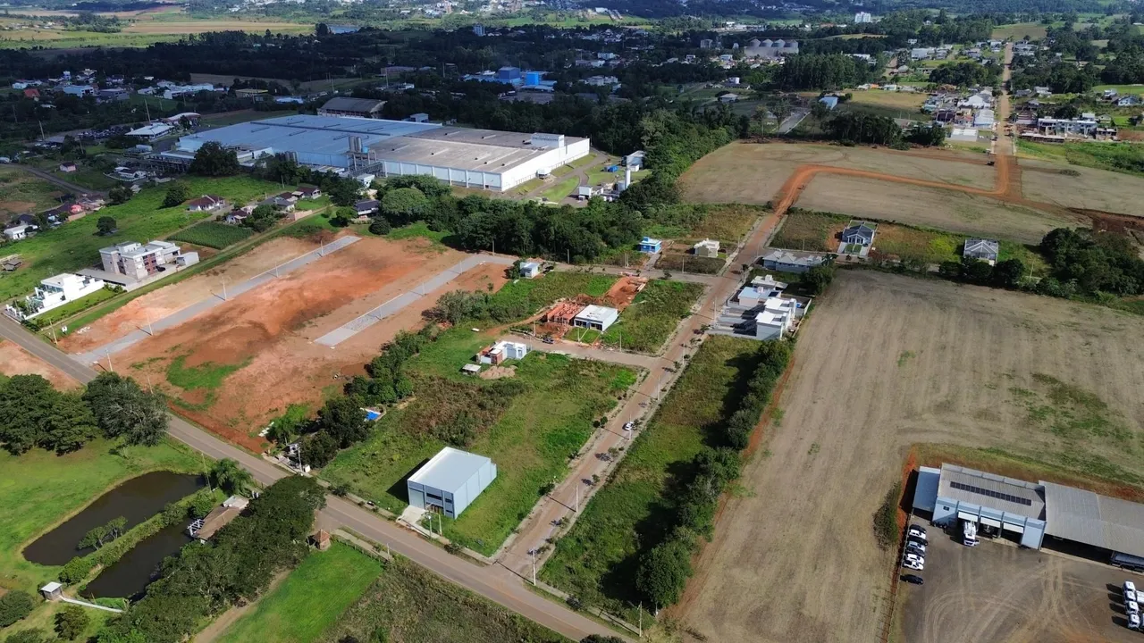 Vista aérea de um terreno rural com campos abertos e algumas estruturas.