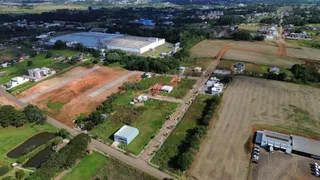 Vista aérea de um terreno rural com campos abertos e algumas estruturas.
