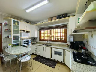 Foto de uma cozinha com armários brancos e bancadas de granito.
