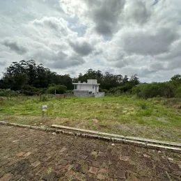 Vista externa de uma residência branca cercada por vegetação em um ambiente rural.