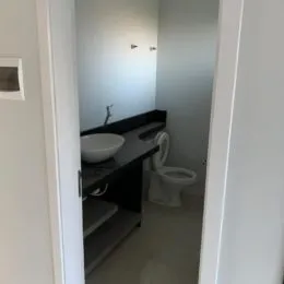 Hall de passagem com paredes brancas e uma bancada escura.