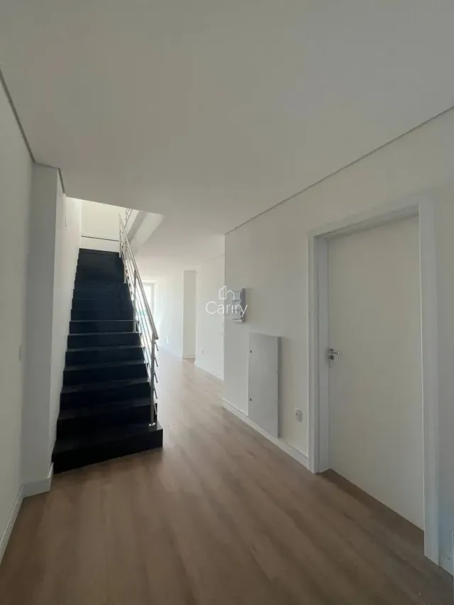 Hall de entrada com escadas e piso de madeira clara.