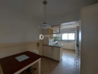 Ambiente interno de uma sala de estar conectada à cozinha em um imóvel no Brasil.