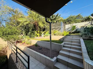 Vista externa de um jardim com degraus e muro de contenção.