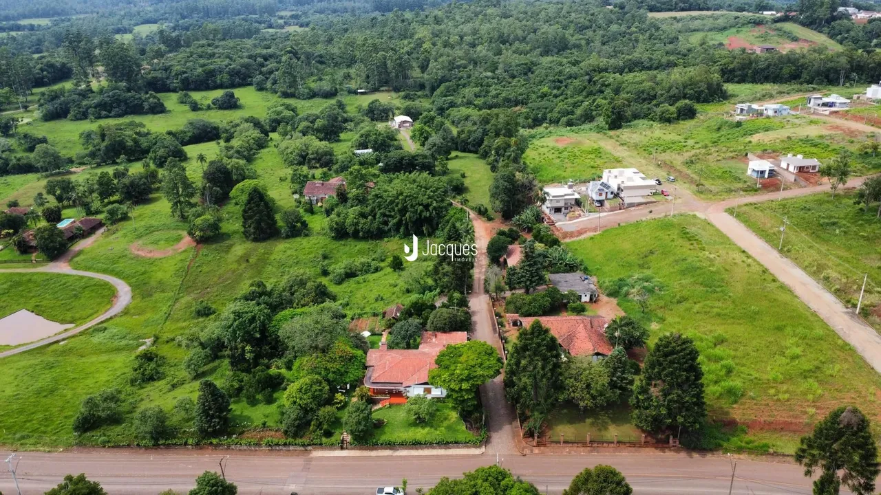 Vista aérea de uma propriedade rural com vegetação densa e algumas construções dispersas.
