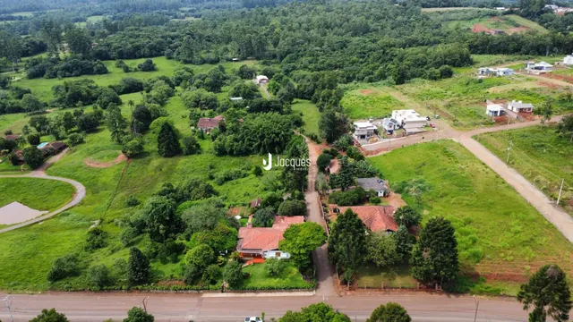 Vista aérea de uma propriedade rural com vegetação densa e algumas construções dispersas.