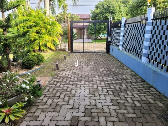 Vista da entrada de uma propriedade com portão e muro de vedação.
