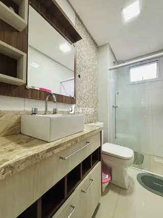 Interior de um banheiro com bancada e box de vidro.