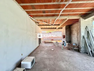 Vista de um corredor interno com estrutura de teto exposta e paredes brancas.