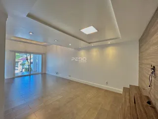 Sala de estar ampla com piso de madeira clara e portas de vidro que dão acesso ao exterior.