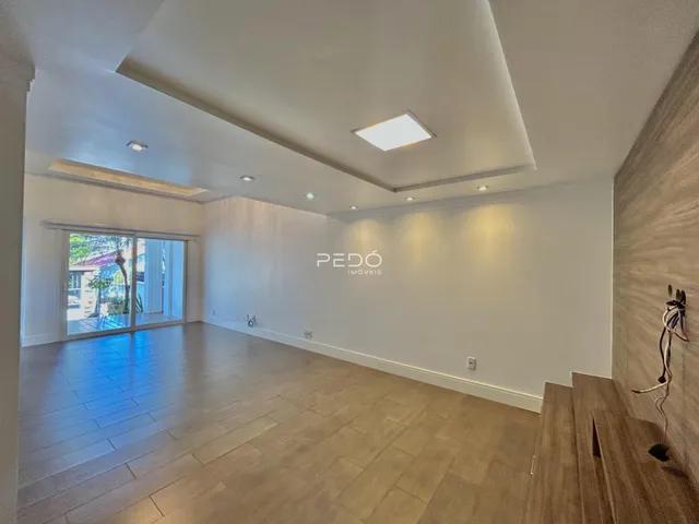 Sala de estar ampla com piso de madeira clara e portas de vidro que dão acesso ao exterior.