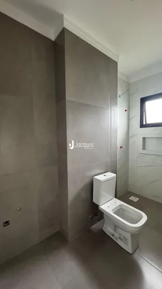 Foto de um banheiro com revestimento de parede cinza e vaso sanitário branco.