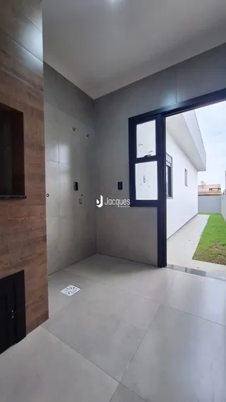 Hall de entrada com piso de concreto e parede de madeira clara.