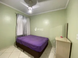 Quarto com cama e piso cerâmico claro.