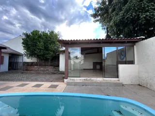 Vista da fachada de uma residência com piscina e área externa.