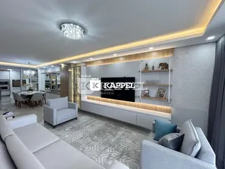 Sala de estar moderna com sofá e painel de TV em um apartamento.