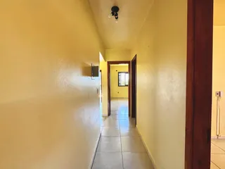 Corredor interno com paredes amarelas e piso de cerâmica.