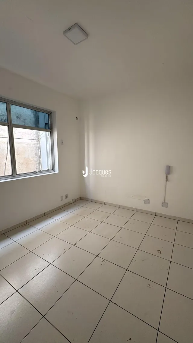 Vista interna de uma sala com piso de cerâmica clara e janela.