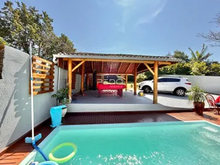Foto de uma área externa com piscina e deck de madeira.
