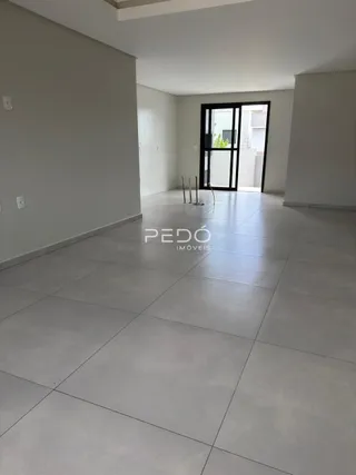 Interior de uma sala ampla com piso claro.