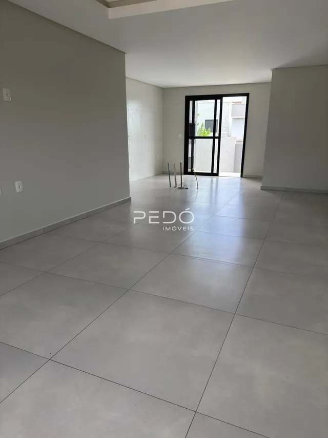 Interior de uma sala ampla com piso claro.