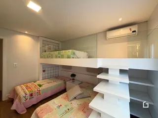Quarto com duas camas e estantes brancas.