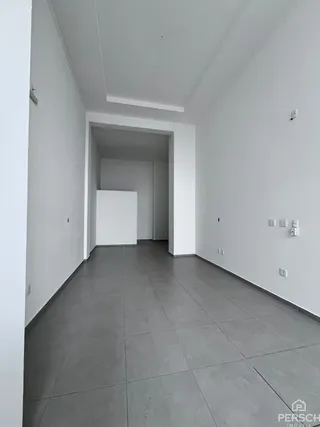 Hall de entrada com piso cinza e paredes brancas.