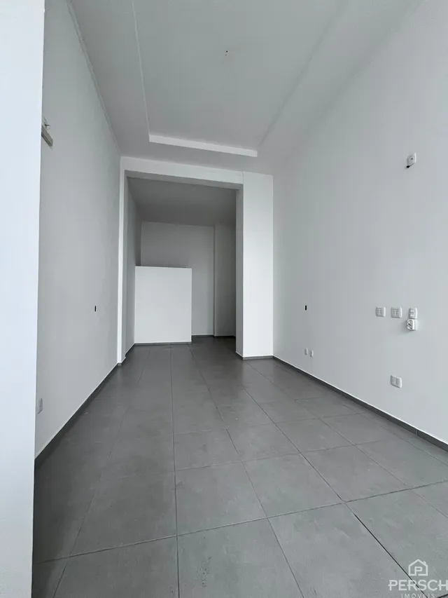 Hall de entrada com piso cinza e paredes brancas.