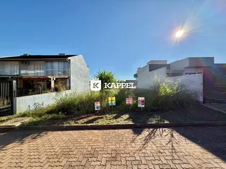 Foto da fachada de uma residência em Lajeado, Brasil, com vegetação alta na frente.