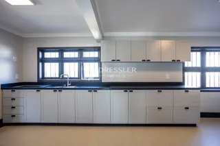 Vista da cozinha com armários brancos e bancada escura.