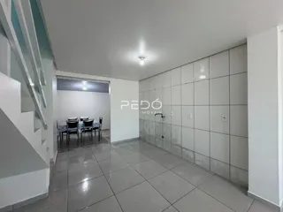 Corredor com piso de cerâmica e parede branca que leva a uma área de jantar.