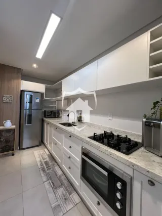 Cozinha moderna com armários brancos e bancadas claras.