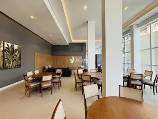 Imagem de um ambiente interno com mesas de jantar de madeira clara.