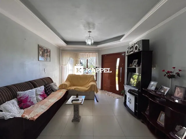 Sala de estar com sofá marrom e poltrona amarela, com janelas cobertas por cortinas claras.