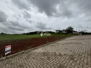 A foto mostra a fachada de uma propriedade com um campo aberto e uma estrada de paralelepípedos.