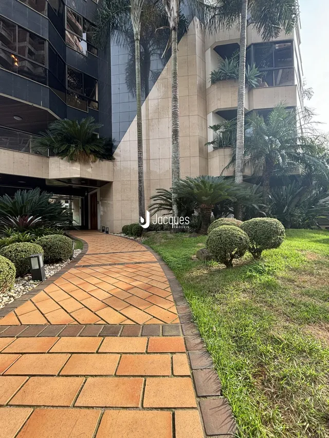Vista da fachada de um edifício residencial em Lajeado, Brasil, com jardim e calçada.
