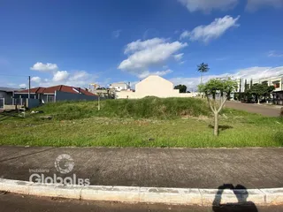 Vista externa de uma propriedade com gramado e vegetação ao lado de uma estrada.